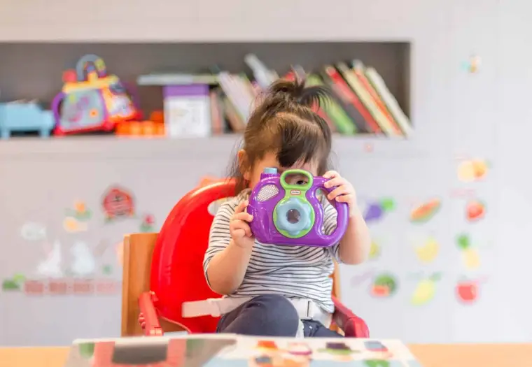 ATSEM aidant des enfants à enfiler des tabliers en école maternelle