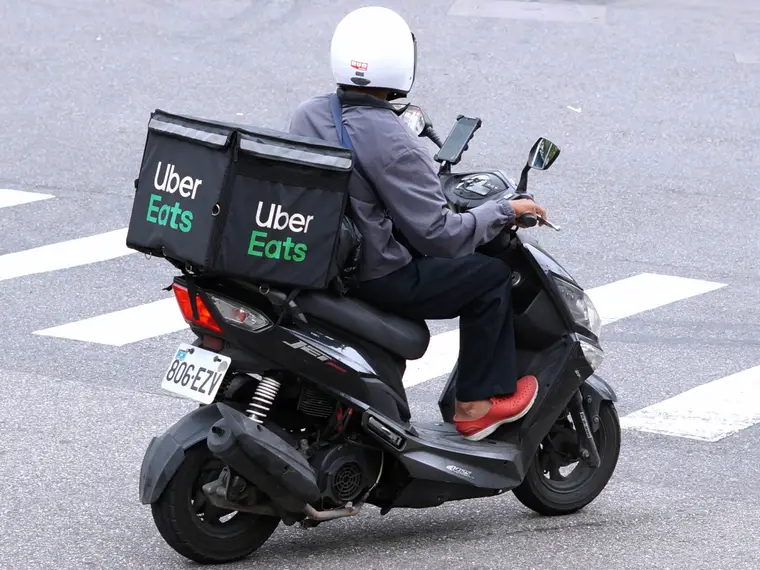 Livreur à vélo préparant son sac isotherme dans une rue française