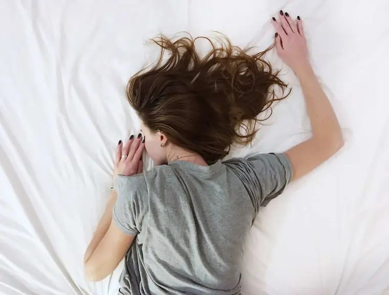 Personne assise calmement au bord d’un lit dans une chambre tamisée