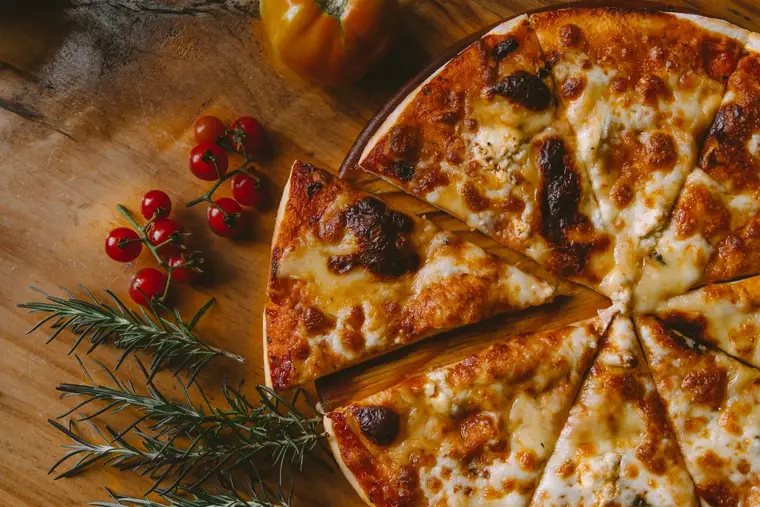 Mains étirant une pâte à pizza sur un plan légèrement fariné