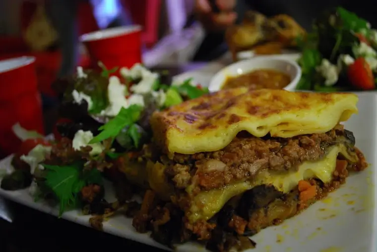 Part de lasagnes au bœuf haché servie après repos dans un plat gratiné