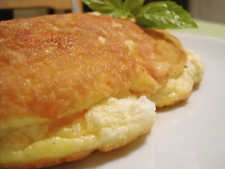 Omelette française roulée et fondante servie sur une assiette blanche