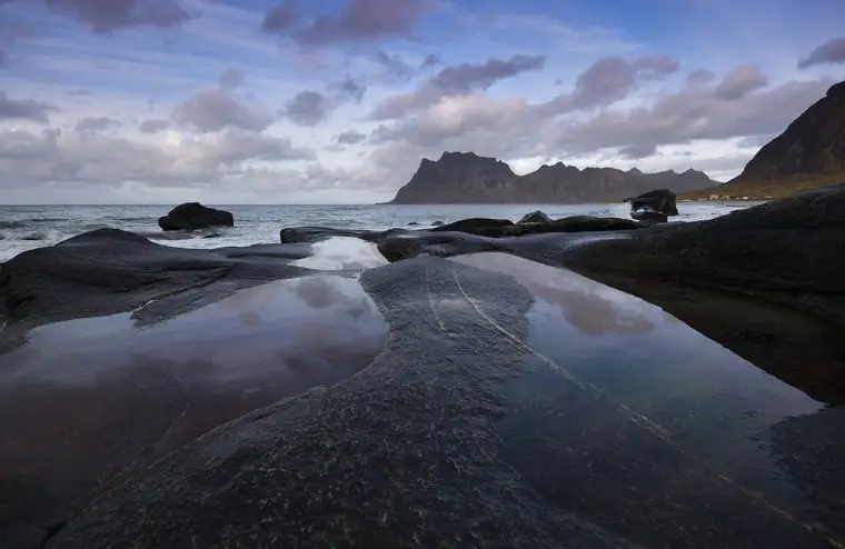 Route côtière longeant un fjord norvégien entre montagnes et cabane de pêcheur
