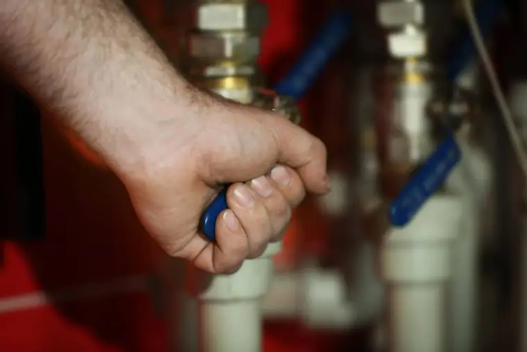 Plombier contrôlant visuellement le groupe de sécurité d’un ballon électrique