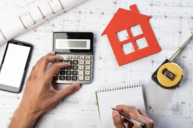 Expert immobilier mesurant le séjour d’une maison lors d’une visite d’évaluation