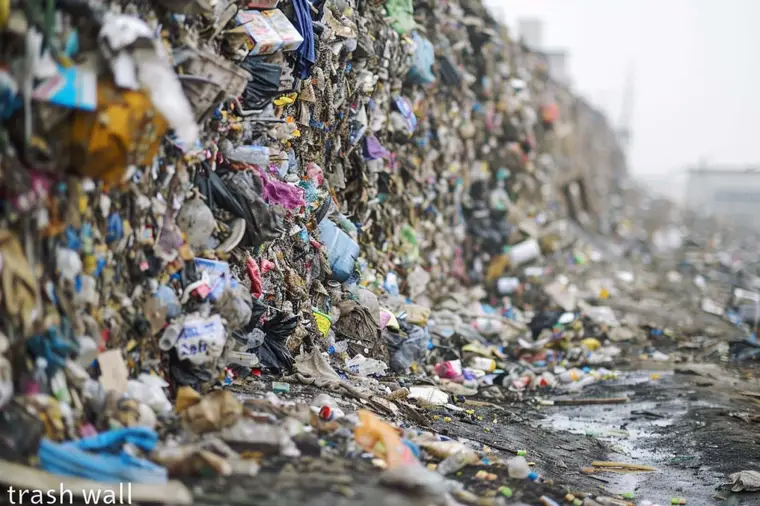 Déchets plastiques accumulés contre une grille au bord d’une rivière