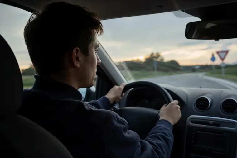 Jeune conducteur attentif au volant sur une route départementale au crépuscule