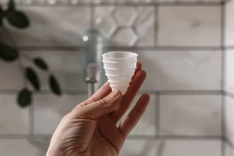 Mains rinçant une cup menstruelle en silicone sous l’eau claire