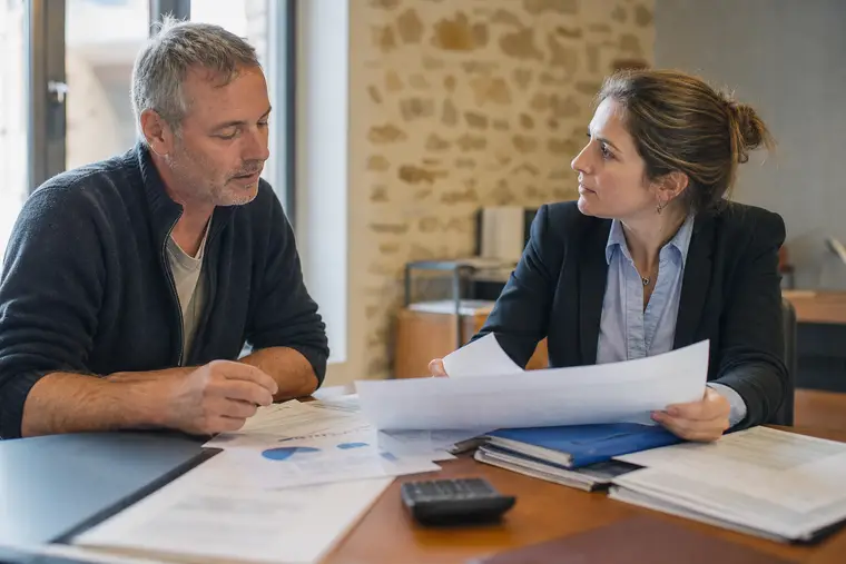 Chef d’entreprise échangeant un dossier de trésorerie avec sa conseillère bancaire