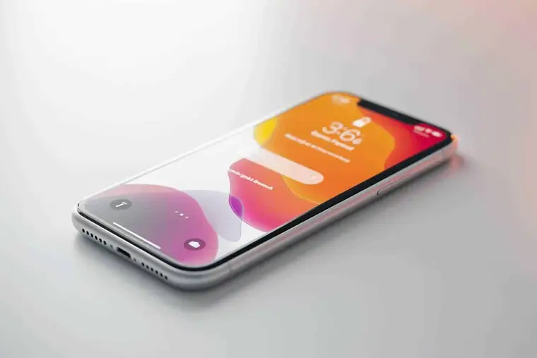 Main rapprochant un iPhone d’un boîtier d’écouteurs sans fil ouvert