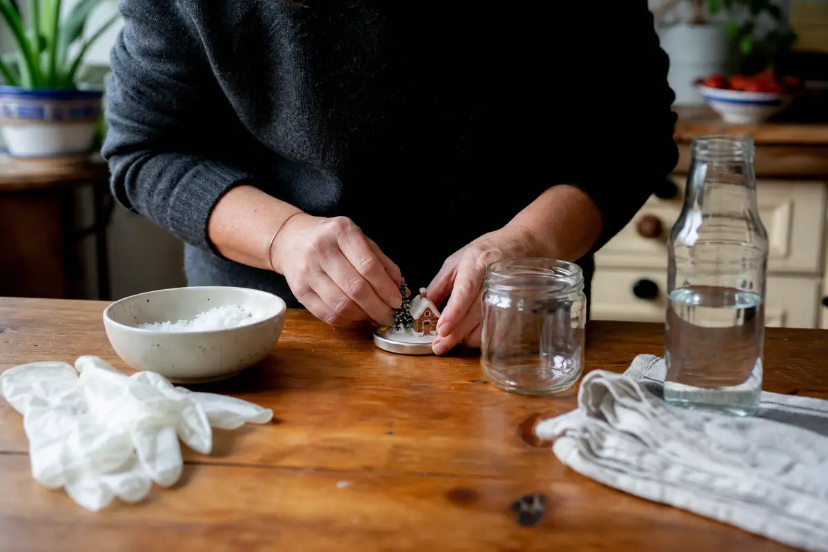Adulte assemblant une boule à neige avec bocal et petite figurine