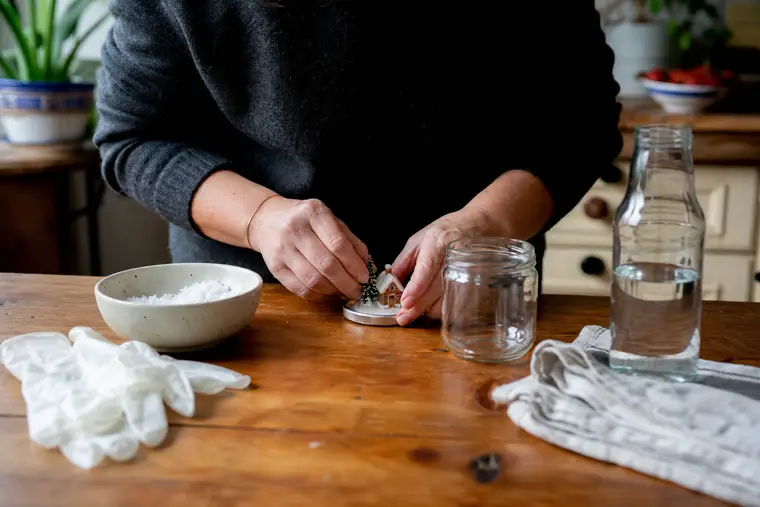Adulte assemblant une boule à neige avec bocal et petite figurine