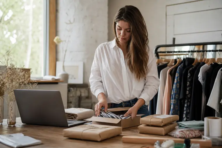 Commerçante préparant des commandes près d’un ordinateur portable dans son atelier