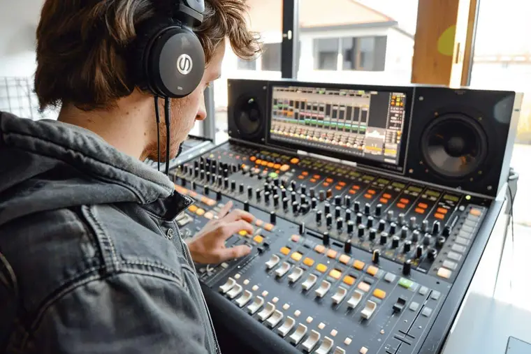 Ingénieur du son réglant une console entre deux enceintes de proximité