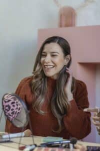 Smiling woman looking at makeup in mirror